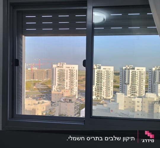חלון עם תריסים חצי סגורים, נוף עירוני ברקע